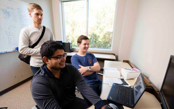 Two Georgia Southern Bachelor of Information Technology students watch a professional code and diagnose network issues during an internship