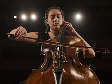 A Georgia Southern Fred & Dinah Gretsch School of Music student performs a cello solo for an audience in an auditorium