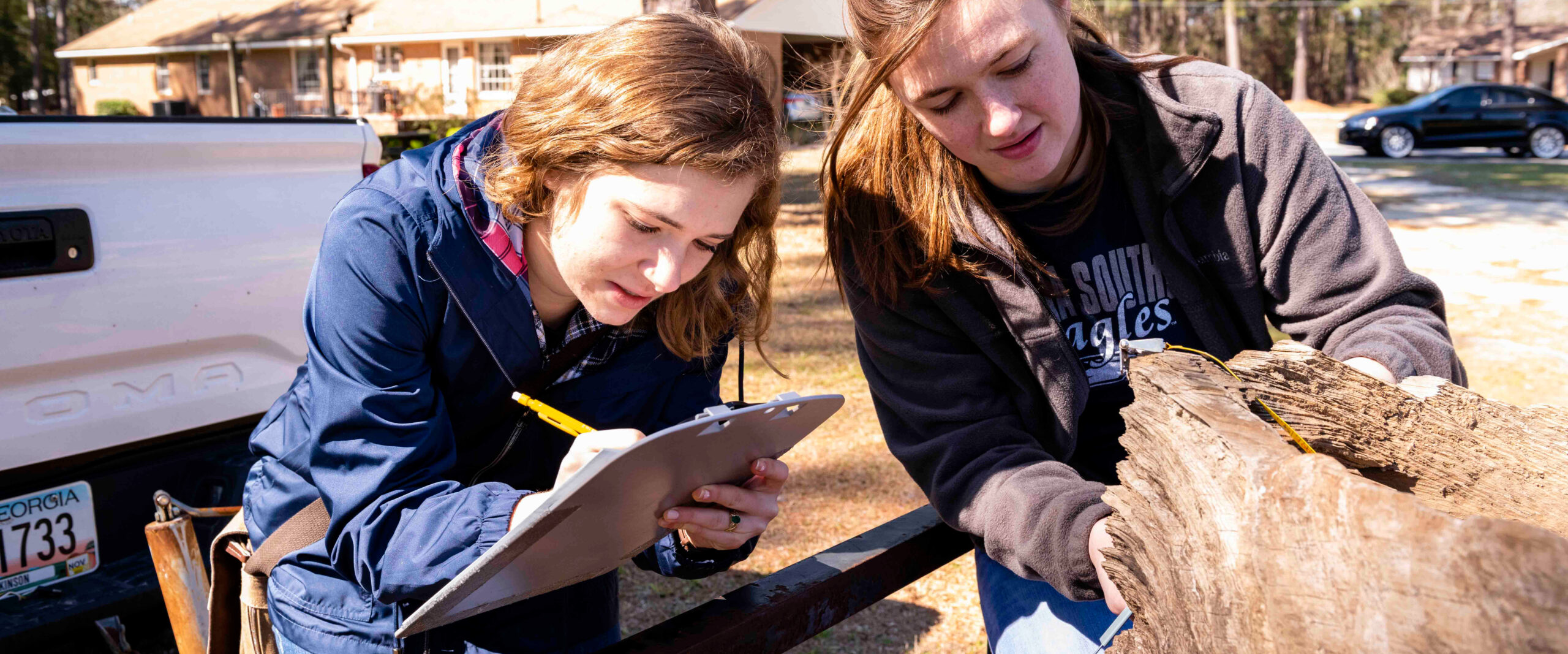 Group of Georgia southern students around a table studying a historical map; hands-on exploration of ancient artifact