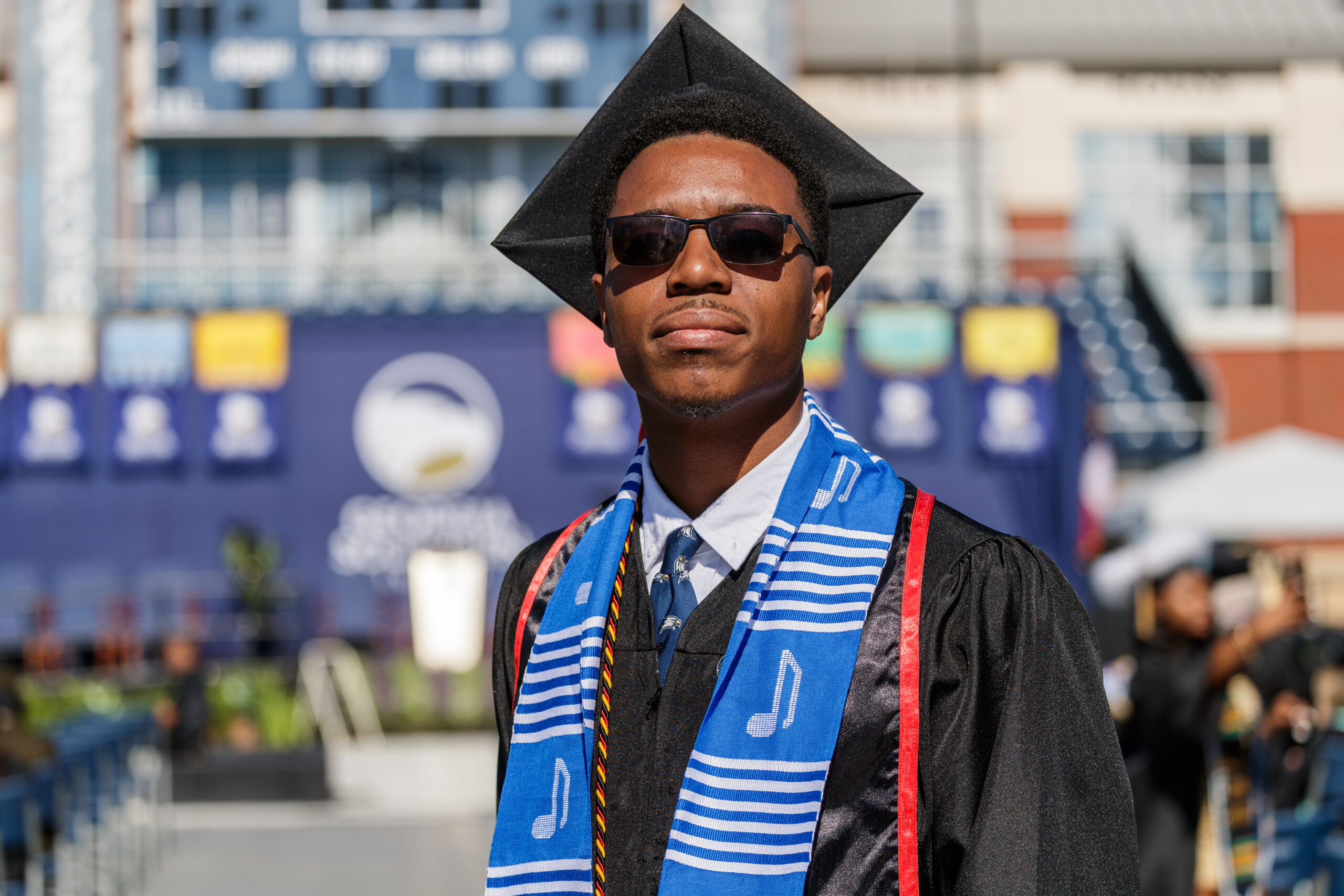 Emam Woods Georgia Southern University graduate wearing a black cap and gown with a blue musical note stole.