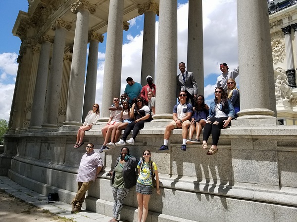 A group photo of students and travelers posing around classical stone columns and monuments outdoors, likely during a study abroad trip.