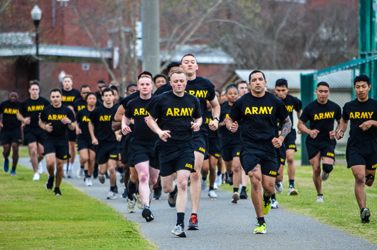 A group portrait of eight smiling military nursing/medical students or ROTC cadets standing outdoors in military physical training/combat uniforms with stethoscopes around their necks.