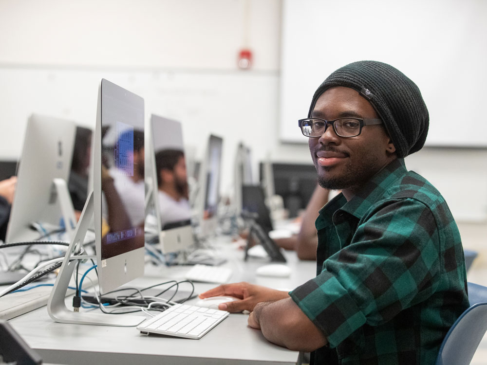 A Georgia Southern scholarship recipient smiles while working on an animation in a fine arts lab.