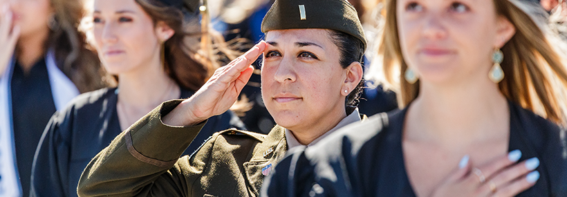 A close-up of a female military service member in uniform rendering a sharp salute during a graduation ceremony.