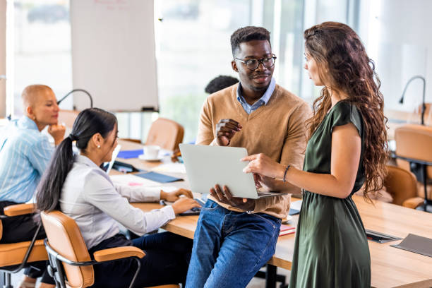 A diverse group of professionals working collaboratively around a conference table in a modern, brightly lit office space.