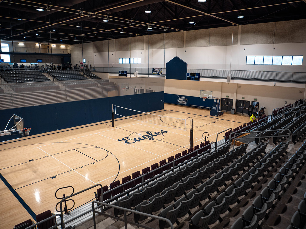 An elevated wide shot of an empty indoor university gymnasium featuring a basketball court with the word 