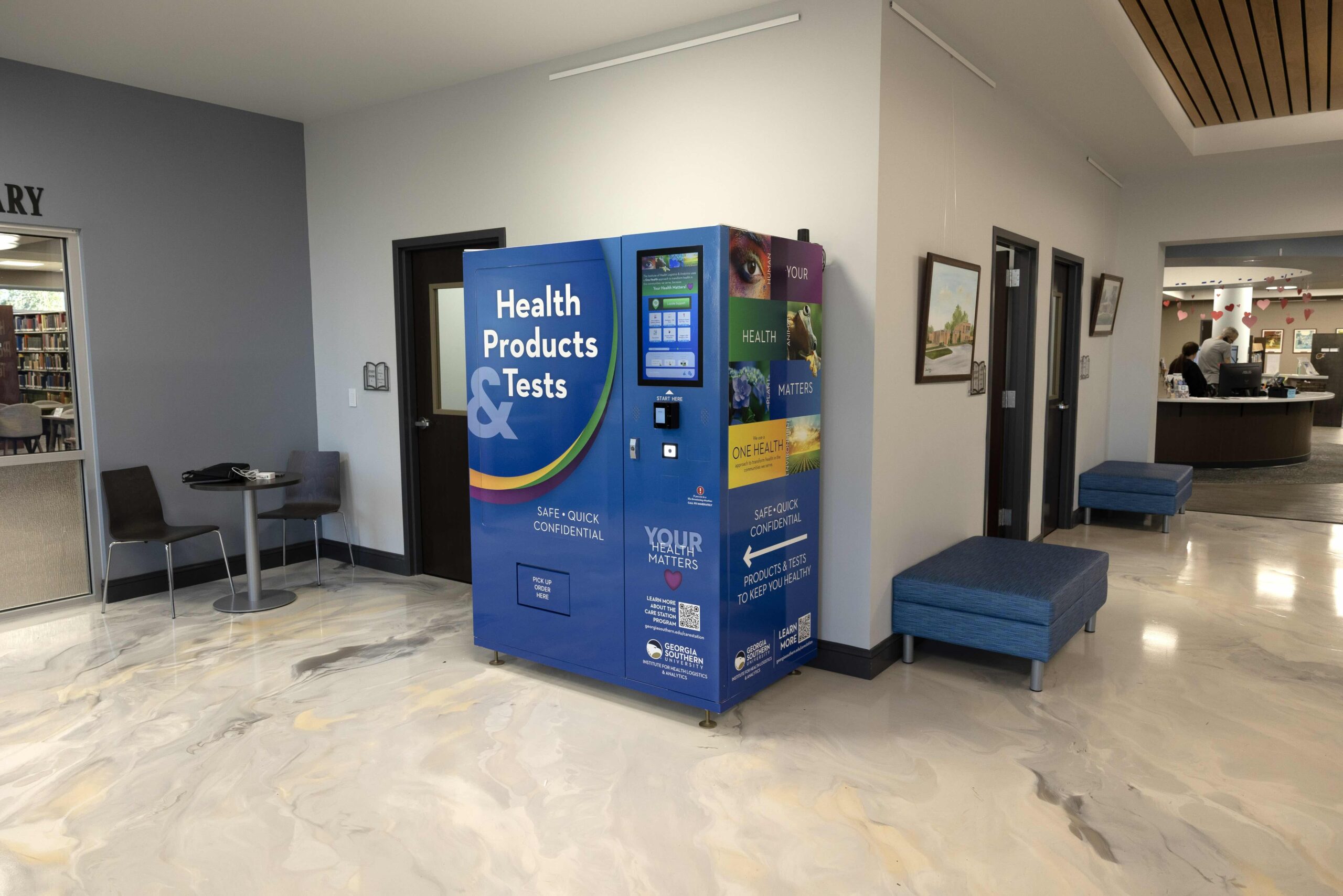 A blue and yellow "Health Products & Tests" vending machine stands in a well-lit hallway at Georgia Southern University, providing students with safe and confidential access to health supplies.