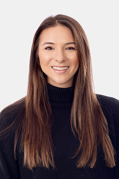 Portrait of a smiling woman with long brown hair wearing a black turtleneck sweater, facing camera.