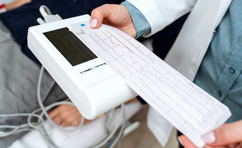 Medical professional holding a printed electrocardiogram (ECG) tracing from a portable monitor.