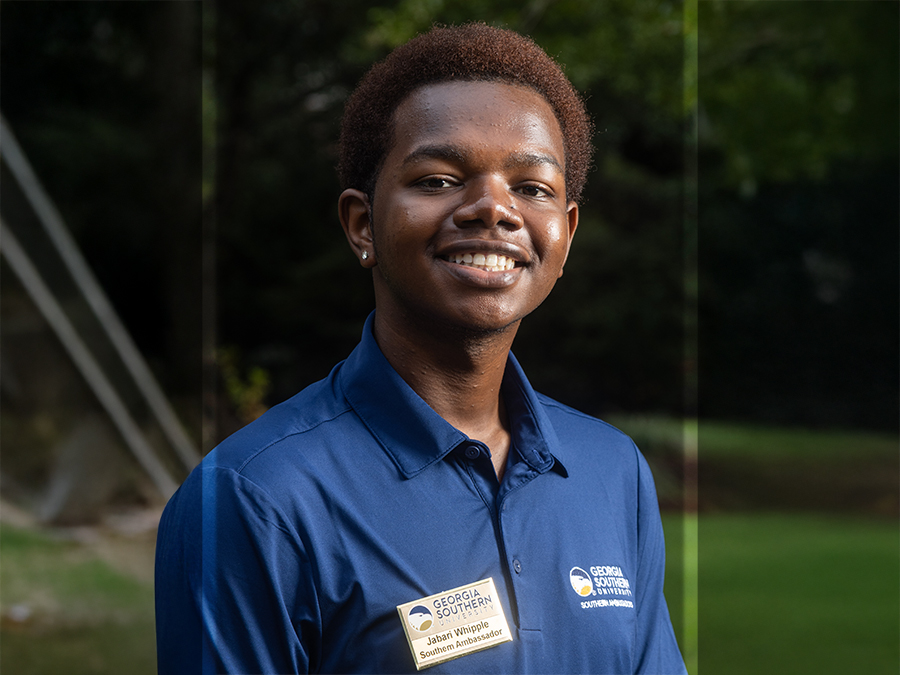 Smiling young man in a blue polo with a Georgia Southern badge, outdoors in a park-like setting.