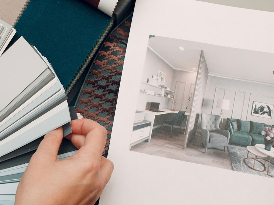 Interior designer holding color swatches and fabric samples next to a room design portfolio.